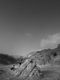 People on rock formation against sky