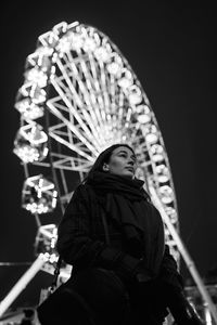 Young beautiful caucasian brunette woman posing by ferris wheel at night. black and white