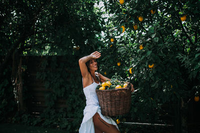 Young woman holding ice cream cone in basket against trees