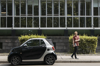 Full length of woman standing against car