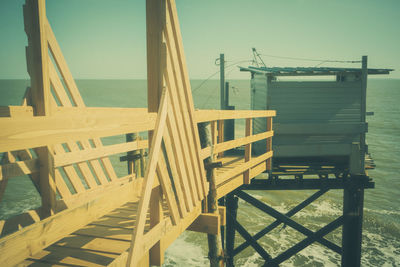 Empty chairs and tables on beach against sky