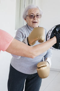 Senior woman boxing with fitness instructor