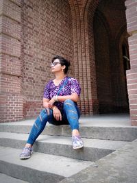 Woman sitting at entrance of historic building