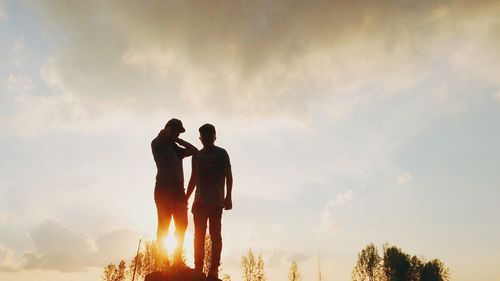 Silhouette of people against cloudy sky