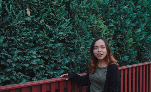 Portrait of smiling young woman standing against tree