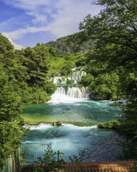 Scenic view of waterfall in forest against sky