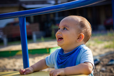 Cute happy smiling baby boy playing at children playground outdoors
