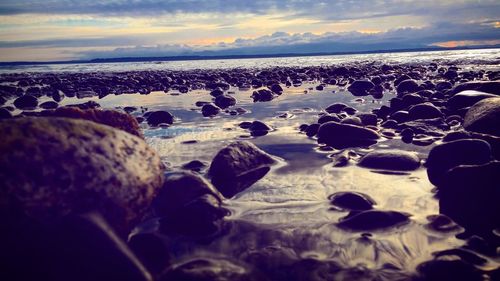 Close-up of pebbles on beach against sky during sunset