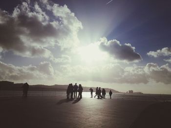 Silhouette people on beach against sky