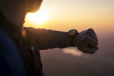 Man checking smart watch at sunset