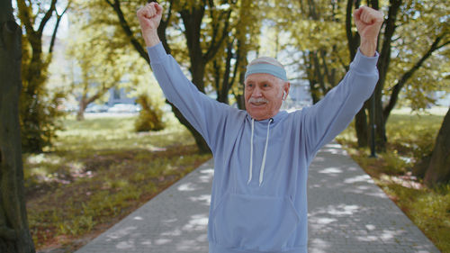 Senior man with arms raised in park