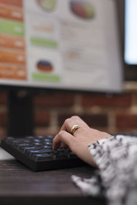 Cropped hand of woman using computer