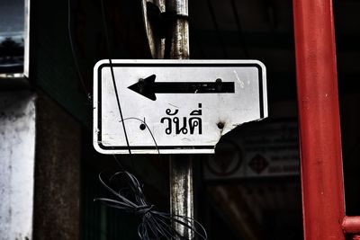 Close-up of arrow symbol on broken signboard