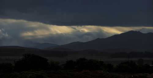 View of trees with mountains against cloudy sky