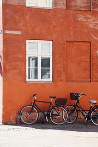 Bicycles parked against red wall