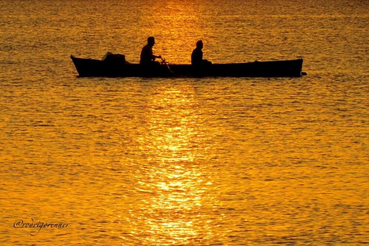 water, silhouette, sunset, men, waterfront, leisure activity, lifestyles, rippled, nautical vessel, orange color, transportation, sea, nature, boat, tranquility, reflection, scenics, beauty in nature