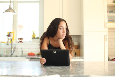 Portrait of young woman using phone at home