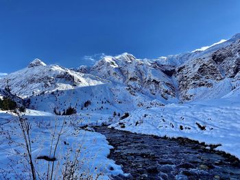 Scenic view of snowcapped mountains against clear blue sky