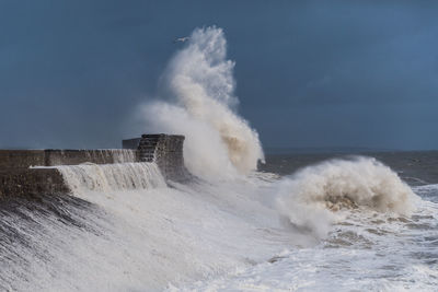 Scenic view of splashing waters in sea against sky