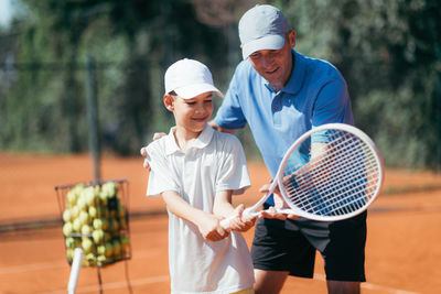 Man instructing boy while standing in tennis court