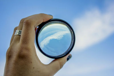 Close-up of hand holding glass against sky