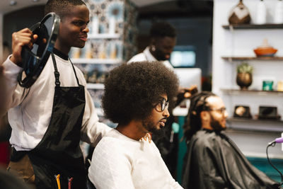 Male barber showing mirror to customer in hair salon