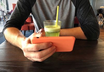 Midsection of man drinking glass on table