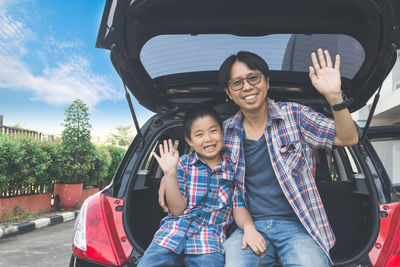 Portrait of happy boy sitting on car