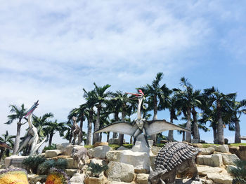 Palm trees by rocks against sky