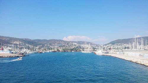 Sea by cityscape against blue sky