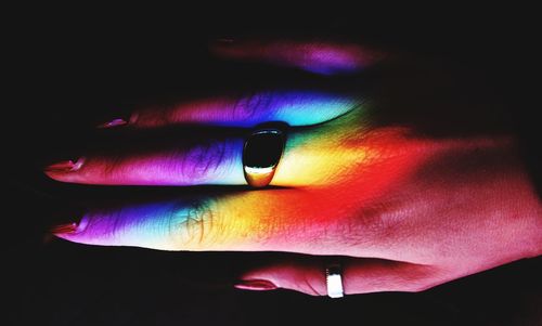 Close-up of hand on multi colored light