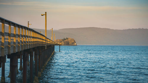 Pier over sea against sky during sunset