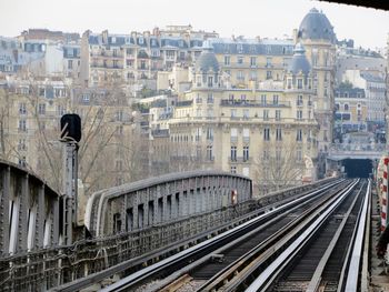 Railroad tracks in city against sky