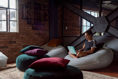 Woman using phone while sitting on laptop