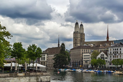 Buildings by river against sky in city