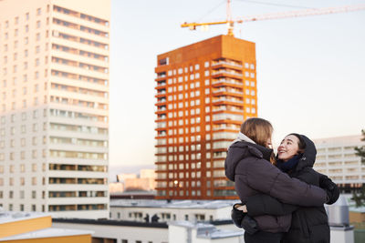 Female couple hugging in modern neighborhood