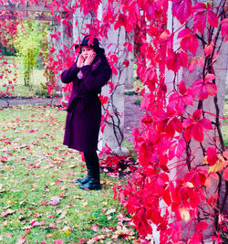 Full length of woman standing against pink leaves