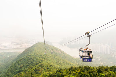 Overhead cable car over mountains against sky