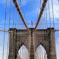 Low angle view of suspension bridge against blue sky