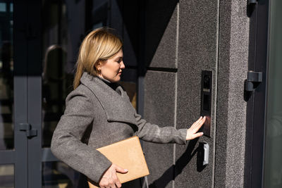 Young woman standing against wall