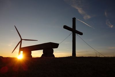 Silhouette windmill on field against sky during sunset