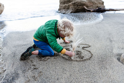 Small child writing i love mum in the sand at a beach in new zealand