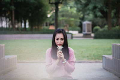 Portrait of young woman sitting on footpath