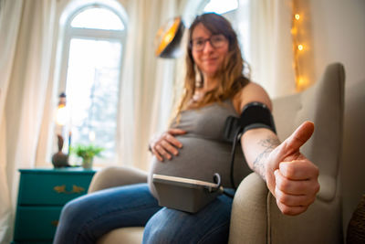 Portrait of smiling woman checking blood pressure at home