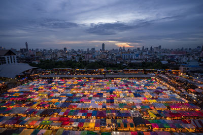 High angle view of illuminated city buildings against sky at sunset