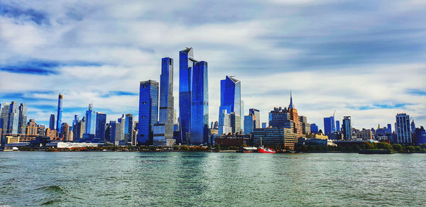 City at waterfront against cloudy sky