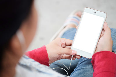 Midsection of woman using mobile phone while sitting outdoors