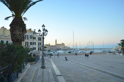 Sailboats in city by sea against clear sky