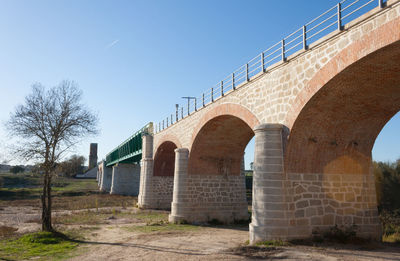 Low angle view of arch bridge against clear blue sky