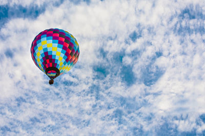 Low angle view of hot air balloons flying against cloudy sky
